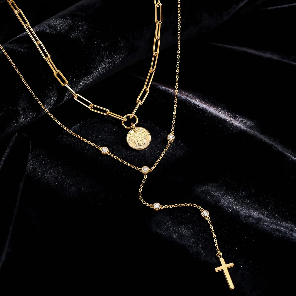 layered gold necklace with symbolic coin and cross accents