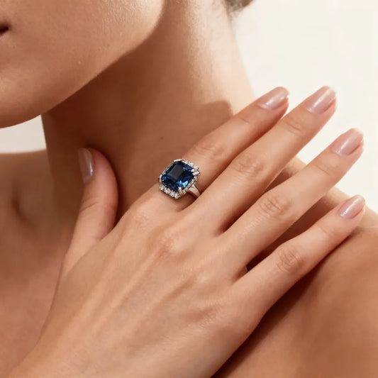 14K white gold ring with a 2.0ct cushion-cut deep blue lab-grown diamond and pavé halo of white diamonds, featuring a simple rounded band.