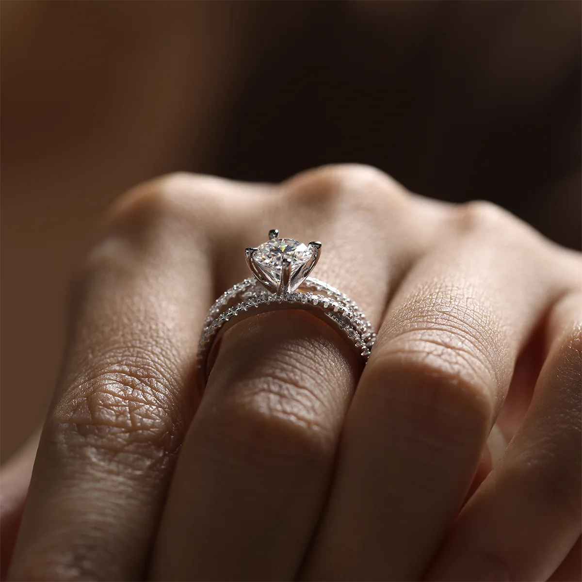 silver moissanite ring with 1ct round center stone and double-row crossover pavé band