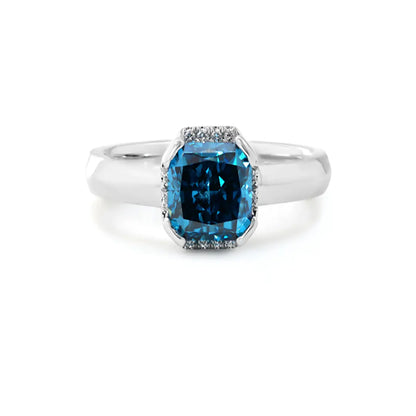 14K white gold ring with a 2.0ct cushion-cut deep blue lab-grown diamond and pavé halo of white diamonds, featuring a simple rounded band.