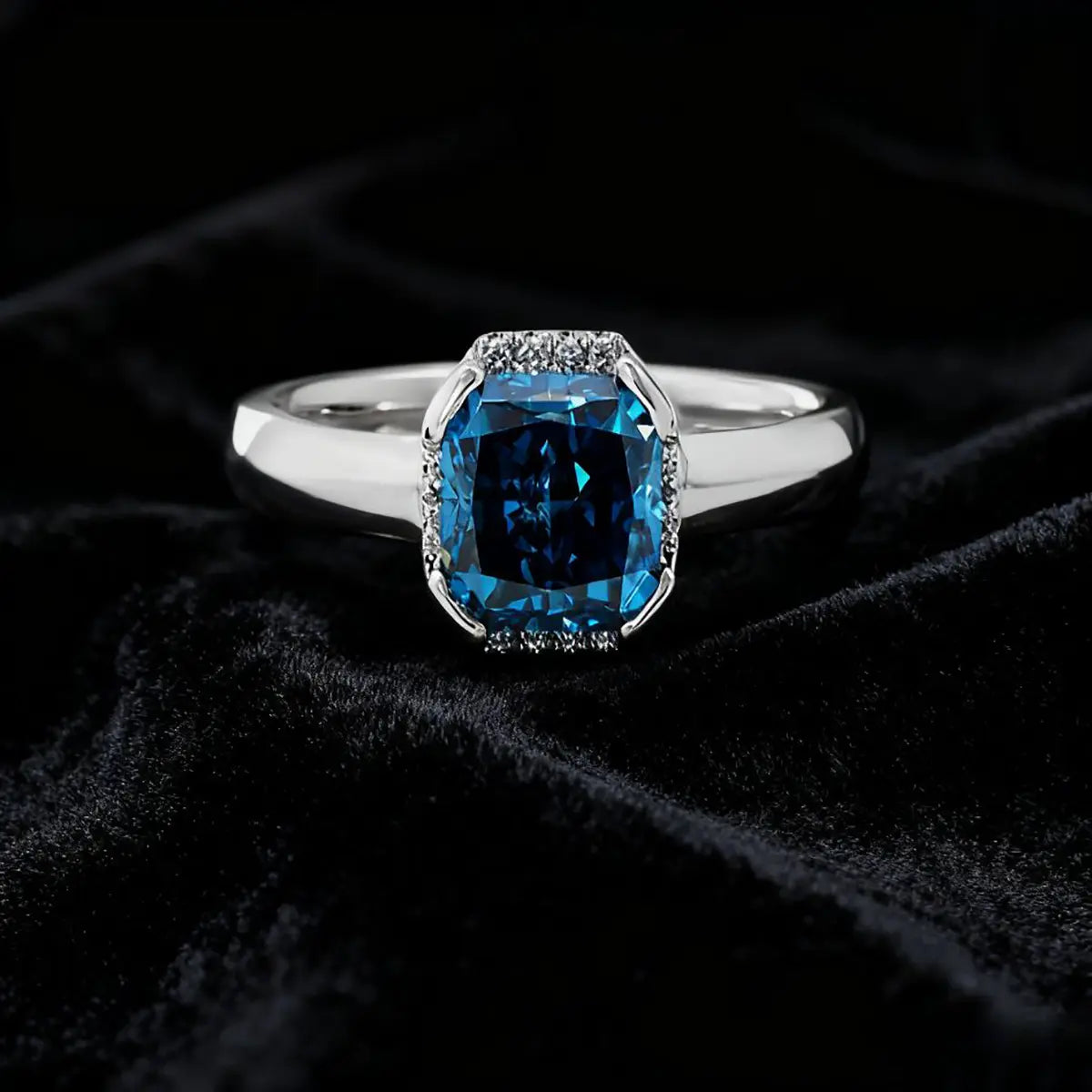 14K white gold ring with a 2.0ct cushion-cut deep blue lab-grown diamond and pavé halo of white diamonds, featuring a simple rounded band.