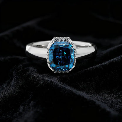 14K white gold ring with a 2.0ct cushion-cut deep blue lab-grown diamond and pavé halo of white diamonds, featuring a simple rounded band.