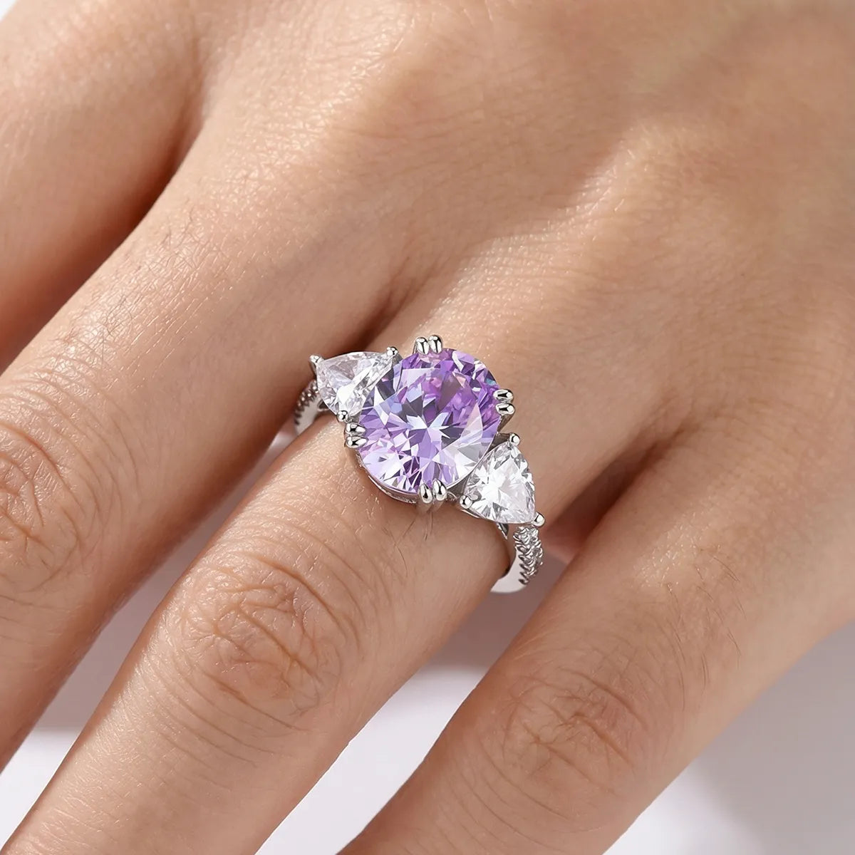 Luminous three-stone engagement ring with 1.8ct oval purple diamond center and pear-shaped white diamond side stones on 14K white gold band
